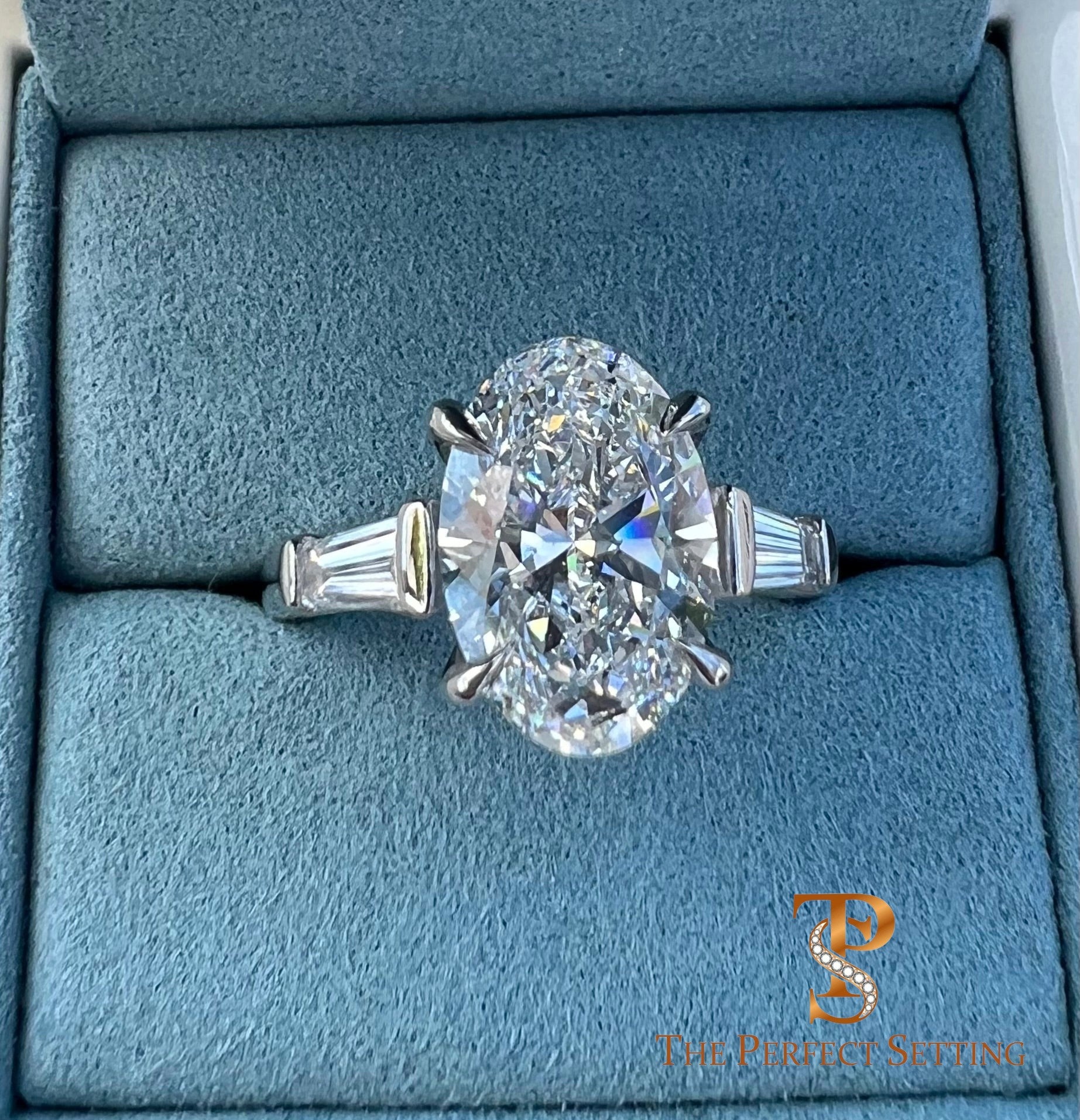 The Perfect Setting, Inc. platinum engagement ring featuring a 3 carat oval diamond with tapered baguette side stones.