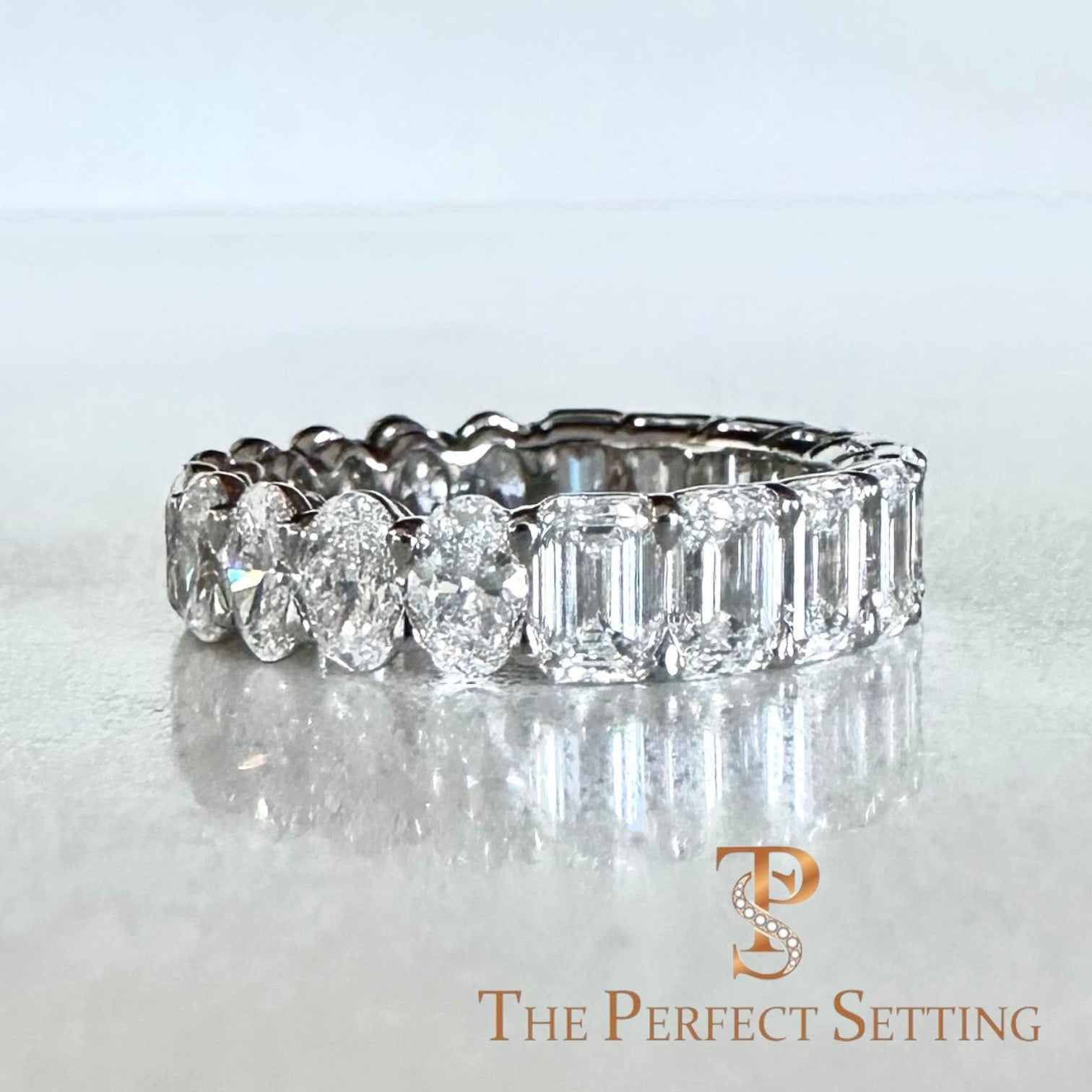 The Perfect Setting, Inc. custom platinum eternity band featuring alternating emerald and oval cut diamonds on a textured background.