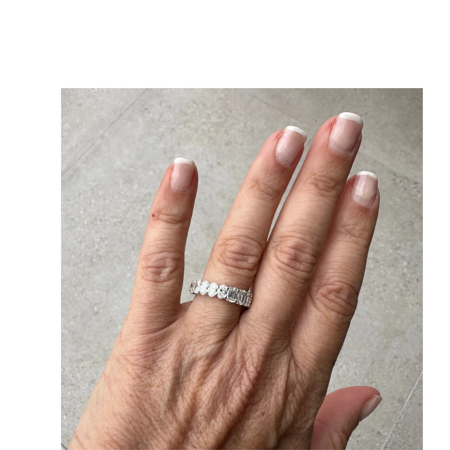 The Perfect Setting, Inc. platinum eternity band featuring alternating emerald and oval cut diamonds on a hand.