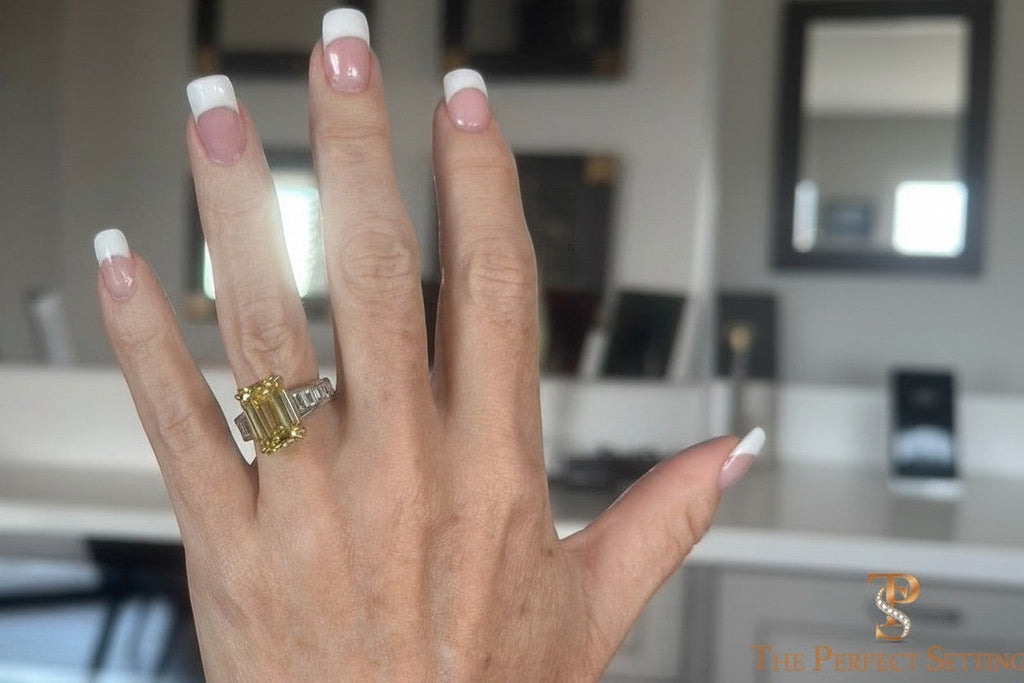 The Perfect Setting, Inc emerald cut vivid yellow diamond engagement ring with baguette side stones on a hand.