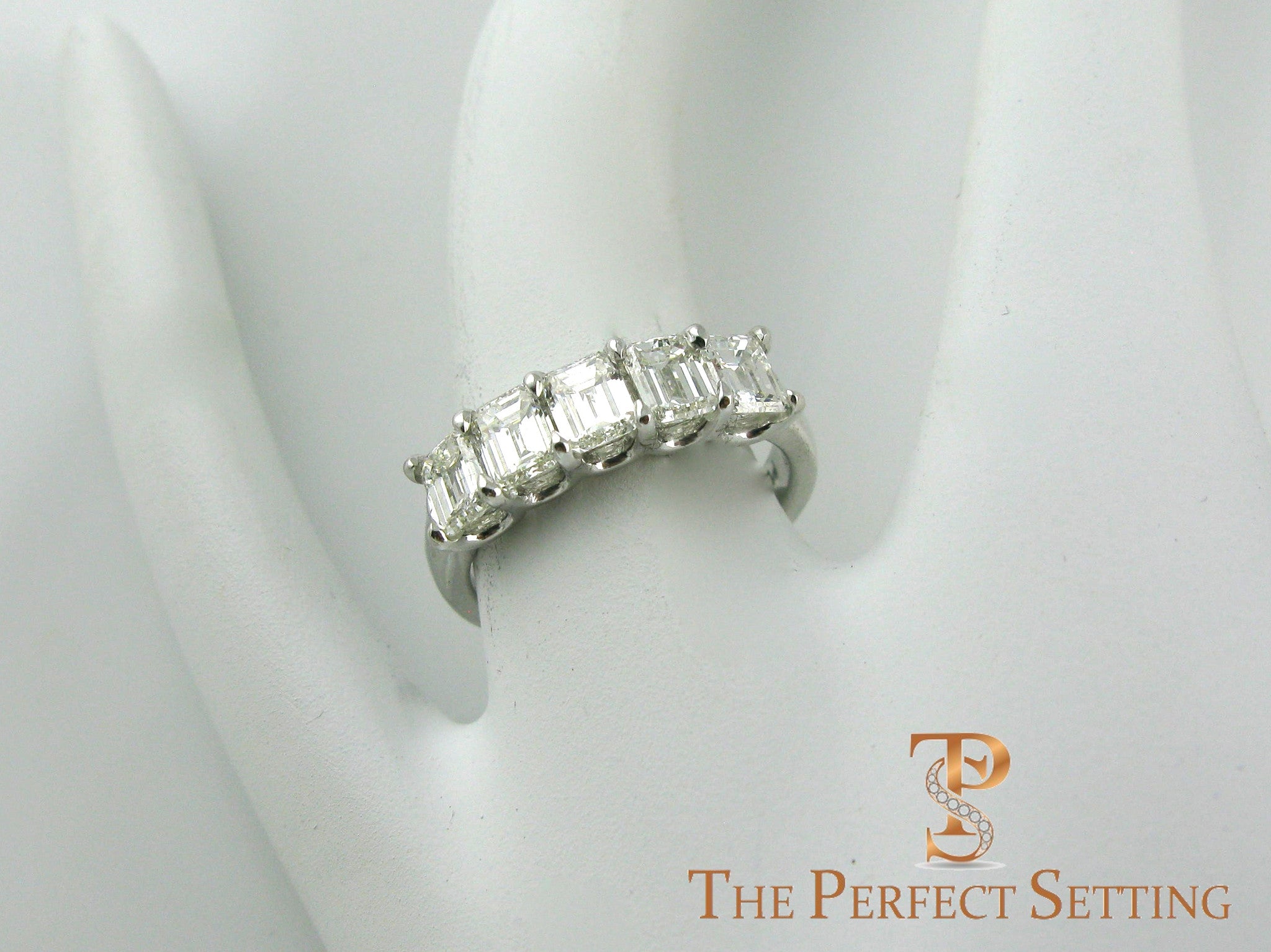 5 stone emerald cut diamond wedding band on finger