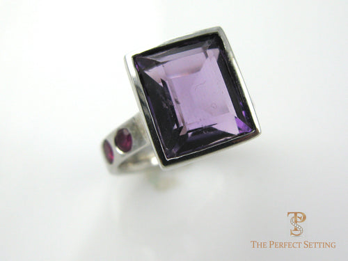 Large amethyst bezel set in 14K white gold with ruby accents
